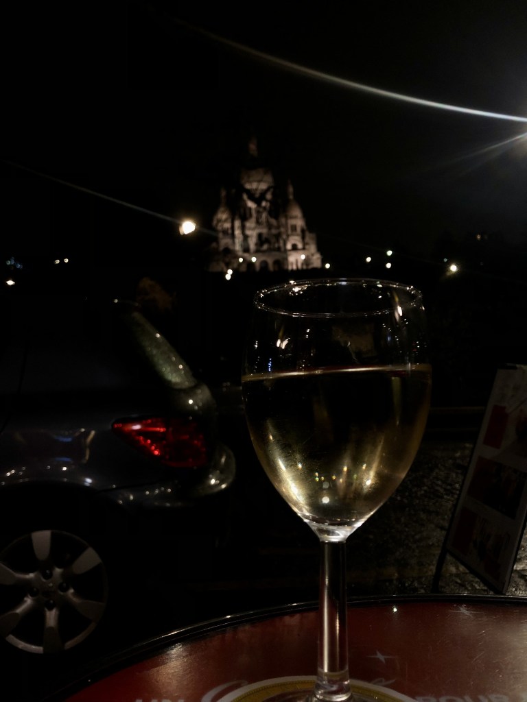 Fotografia di un calice di vino a un cafè di parigi con vista sul sacro cuore